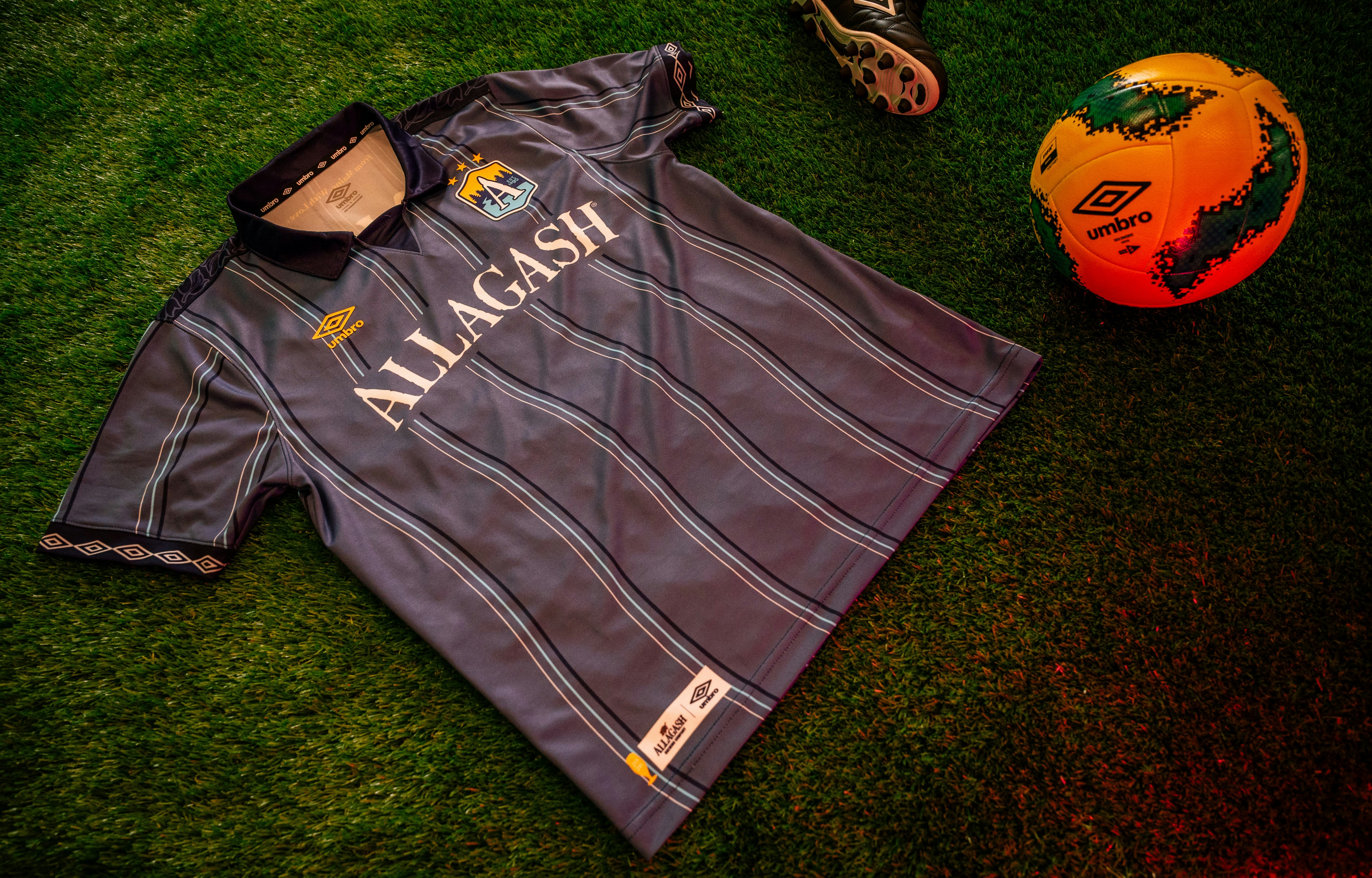 a blue stripe jersey on astroturf with a brightly colored soccer ball
