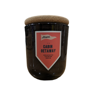 A glass jar candle with a label that reads "Cabin Getaway"