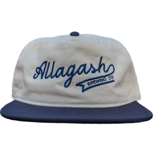 The front of a ballcap featuring the text "Allagash Brewing Co." in blue on a cream cap.