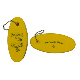 An oval shaped yellow keychain featuring a seagull with a word bubble that reads "Allagash". The opposite side features and anchor and the text "Portland Maine"