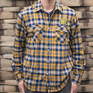 front of yellow and blue Flannel shirt worn by a model. Above the wearer's left chest pocket is an embroidered black and yellow patch with Bravery Brewing Co.'s logo.