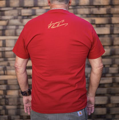 back of Gunny red t-shirt worn by a male model. The text "Semper Fi R. Lee Ermey" in a handwritten script is printed small below the back collar in yellow ink.