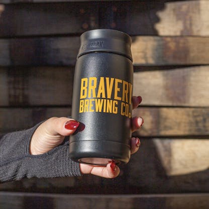 Black Bravery CamelBak – 12oz. The text "Bravery Brewing Co." is printed on the side in yellow. The bottle is held by a hand.