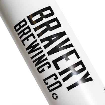Detail photo of a white water bottle on a white background. The water bottle is white with a black lid, and black decals on either side. This detail shows a decal that is the logo for Bravery.