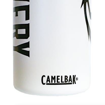Detail photo of a white water bottle on a white background. The water bottle is white with a black lid, and black decals on either side. This detail shows a decal of the manufacturer's logo, Camelbak.