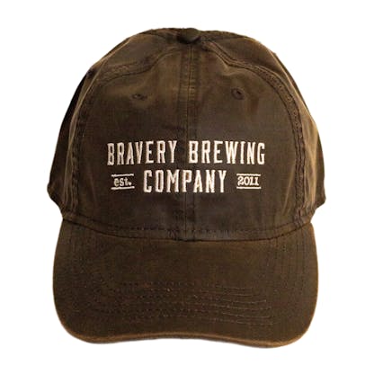 Front photo of brown baseball cap on a white background. The hat is a lightly worn weathered material with white embroidered text across the front two panels that says "BRAVERY BREWING COMPANY est 2011."