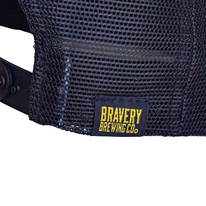 Detail photo of the sewn on black and yellow tag that says "Bravery Brewing Co."