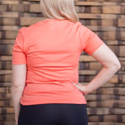 Photo of a person wearing a shirt facing away from the camera. The shirt is coral in color.