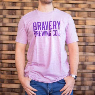 Photo of a person wearing a shirt facing the camera. The shirt is a heather lilac in color with the text "Bravery Brewing Co." printed in dark purple large across the chest.