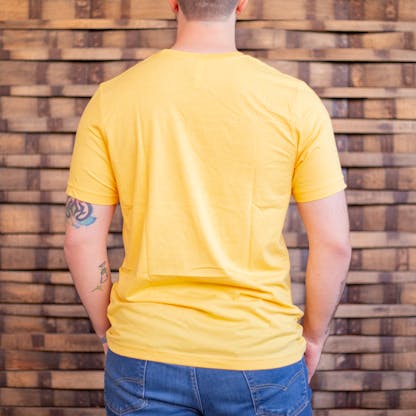 Photo of a person wearing a shirt facing away from the camera. The shirt is yellow in color.